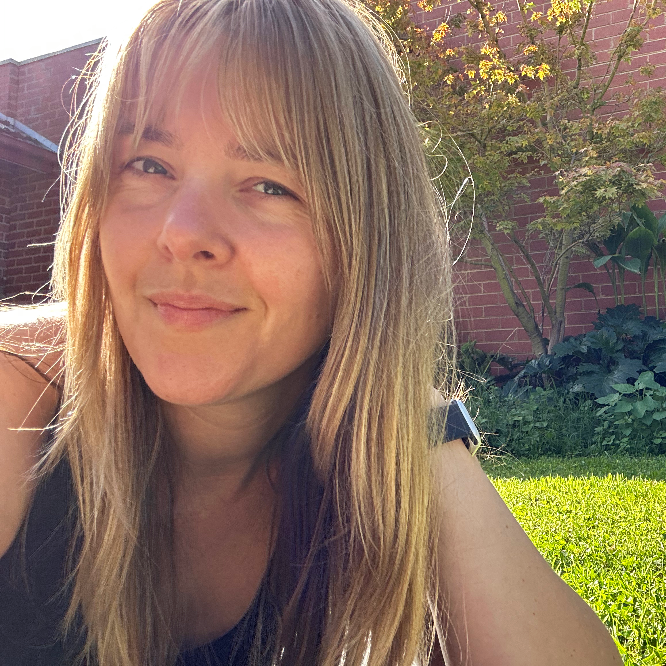 Photo of a smiling woman in a grassy backyard