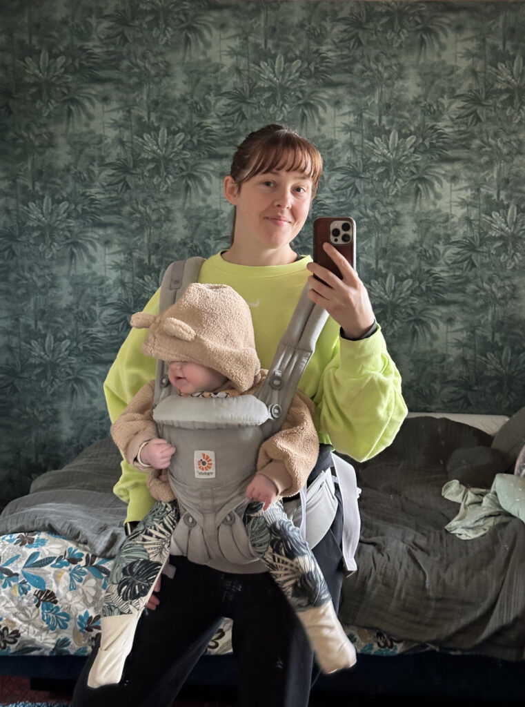 Photo of a woman taking a selfie with a baby in a front pack